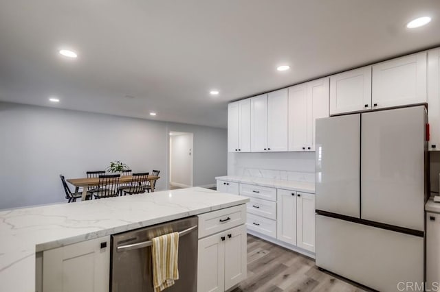 kitchen with white refrigerator, dishwasher, light stone countertops, and white cabinets