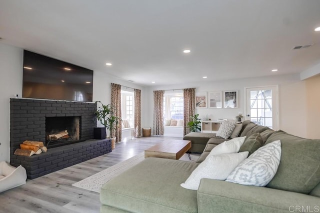 living room featuring a brick fireplace and light wood-type flooring