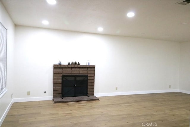 unfurnished living room featuring a fireplace and light hardwood / wood-style floors