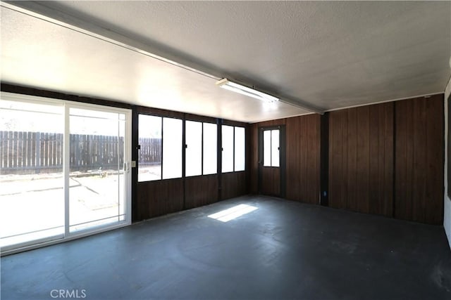 spare room with plenty of natural light, concrete floors, and wooden walls