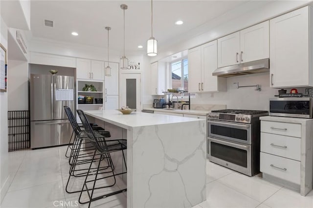 kitchen featuring appliances with stainless steel finishes, decorative light fixtures, white cabinets, a center island, and light stone counters