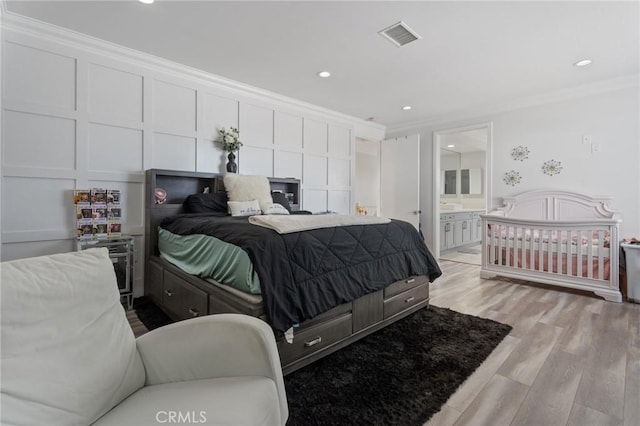 bedroom featuring ensuite bath, ornamental molding, and light hardwood / wood-style floors