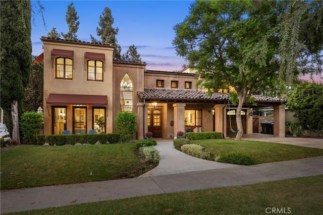 mediterranean / spanish house featuring a carport and a lawn