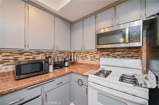 kitchen featuring white gas range, decorative backsplash, and gray cabinetry