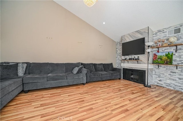 living room with a large fireplace, high vaulted ceiling, and light wood-type flooring