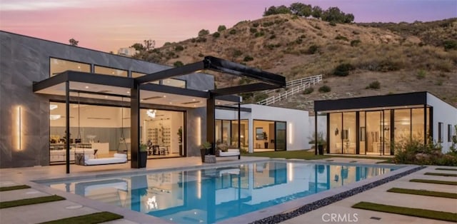 back house at dusk with a mountain view and a patio area