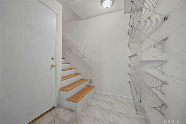 stairway featuring a textured ceiling