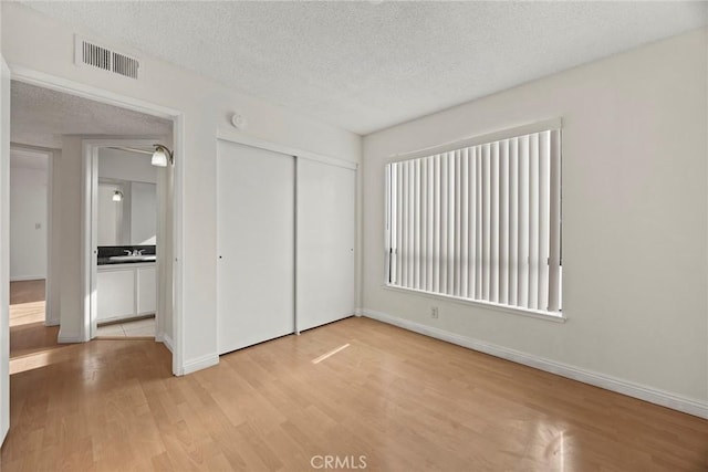 unfurnished bedroom featuring light hardwood / wood-style floors, a closet, and a textured ceiling