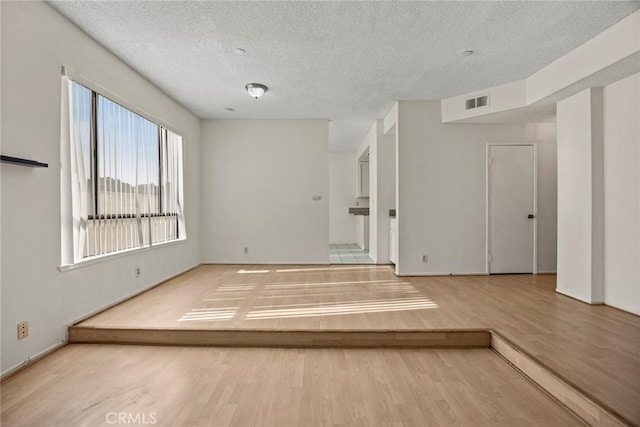 spare room with a textured ceiling and light hardwood / wood-style floors