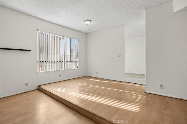 spare room featuring wood-type flooring and a textured ceiling