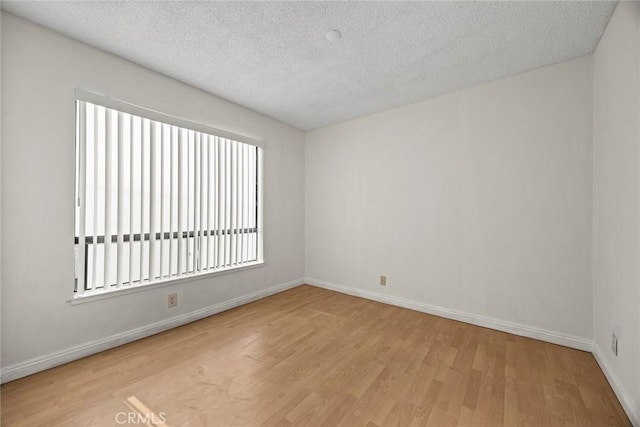 unfurnished room featuring light hardwood / wood-style floors and a textured ceiling