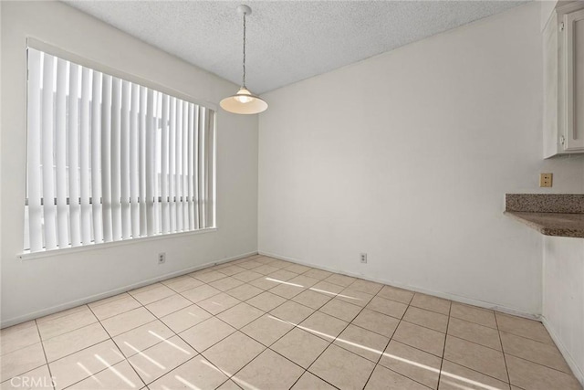 unfurnished dining area featuring light tile patterned floors and a textured ceiling