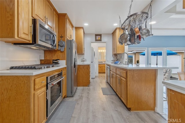 kitchen featuring sink, stainless steel appliances, light hardwood / wood-style floors, and a breakfast bar