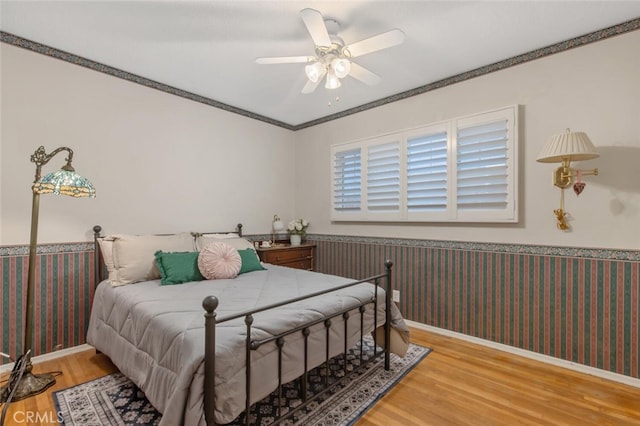 bedroom with crown molding, ceiling fan, and hardwood / wood-style floors