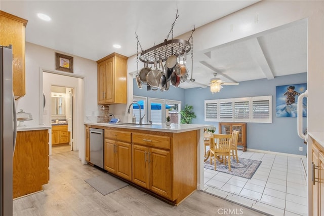 kitchen featuring sink, kitchen peninsula, beamed ceiling, ceiling fan, and stainless steel appliances