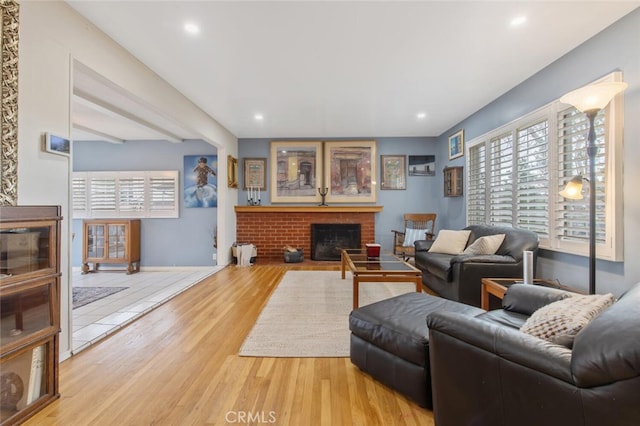 living room with a brick fireplace and light wood-type flooring