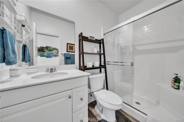 bathroom with walk in shower, wood-type flooring, vanity, and toilet