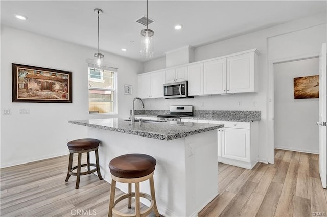 kitchen with white cabinets, appliances with stainless steel finishes, sink, and stone counters