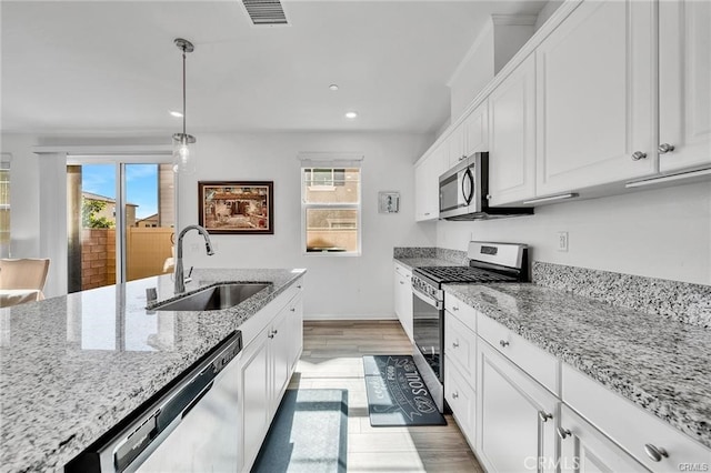 kitchen with pendant lighting, white cabinetry, sink, light stone counters, and stainless steel appliances