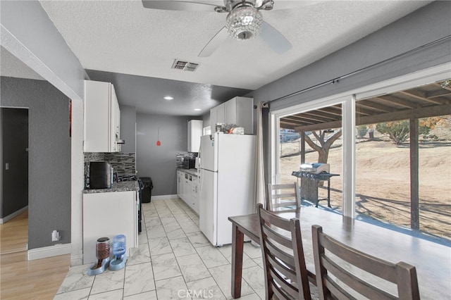 kitchen featuring white cabinetry, ceiling fan, white fridge, and a textured ceiling