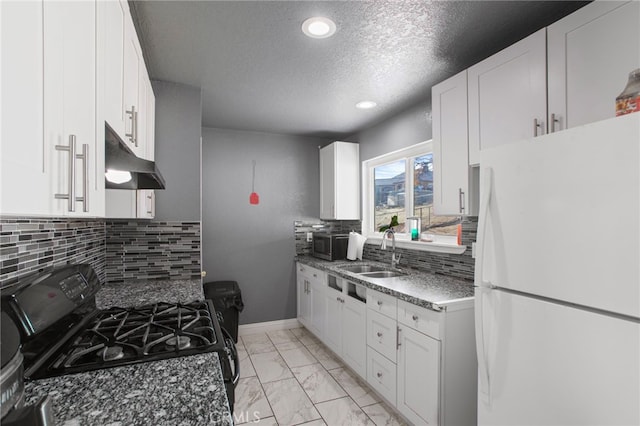 kitchen with white cabinetry, sink, dark stone countertops, white refrigerator, and black gas stove