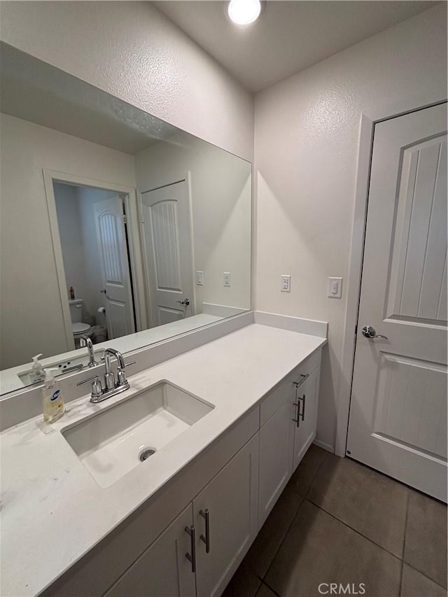 bathroom featuring vanity, tile patterned floors, and toilet