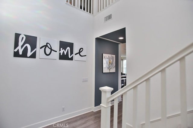 stairs with hardwood / wood-style flooring and a high ceiling