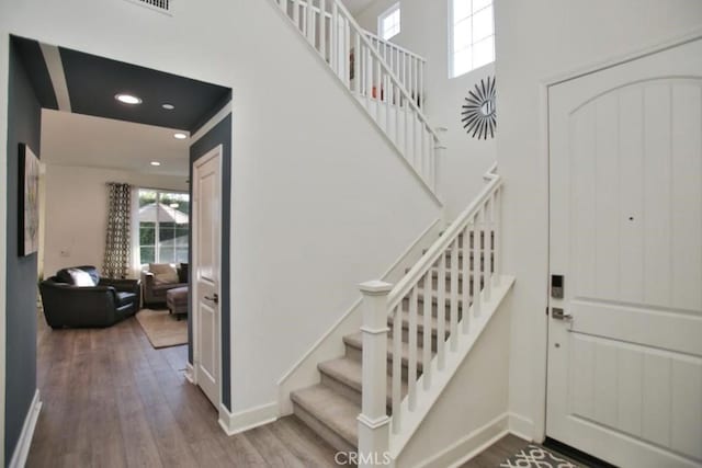 stairway featuring a towering ceiling and hardwood / wood-style floors