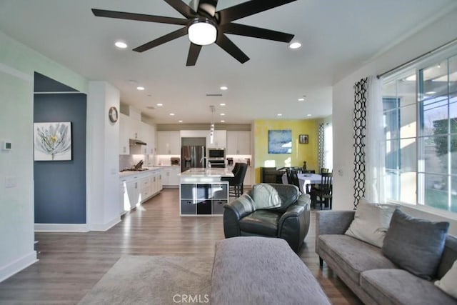 living room featuring hardwood / wood-style flooring, sink, and ceiling fan