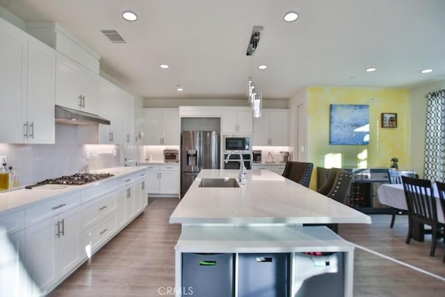 kitchen with stainless steel appliances, an island with sink, and white cabinetry