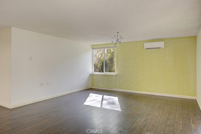 spare room with a wall mounted air conditioner, dark hardwood / wood-style floors, and a textured ceiling