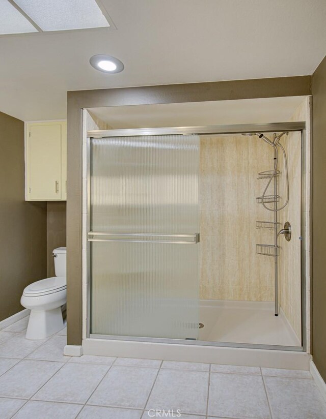 bathroom with tile patterned flooring, walk in shower, and toilet