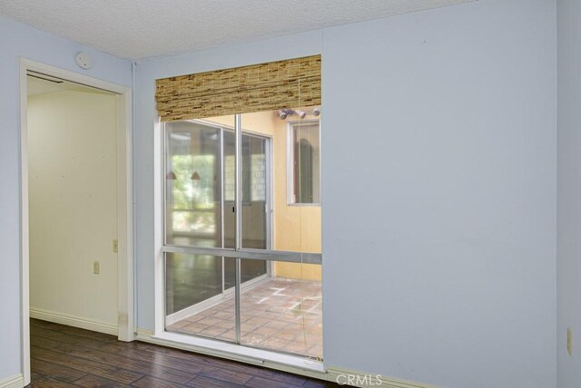 empty room with dark wood-type flooring and a textured ceiling