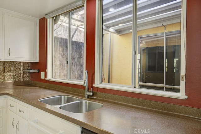 kitchen featuring sink, decorative backsplash, and white cabinets