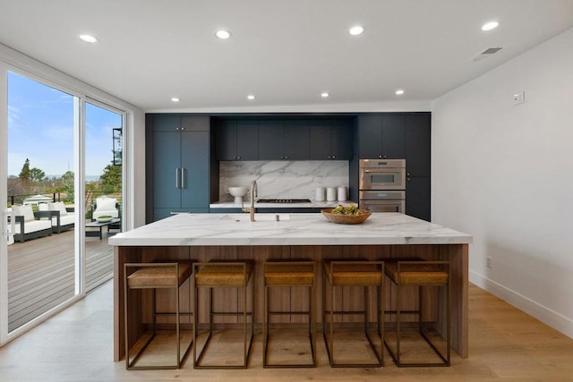 kitchen with a large island, decorative backsplash, and a breakfast bar area