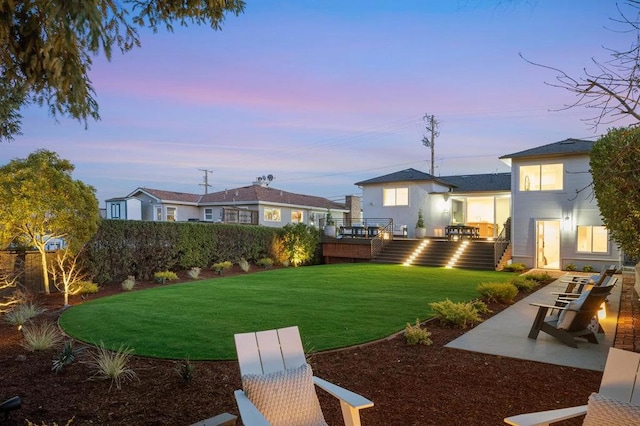 yard at dusk featuring a deck and a patio area