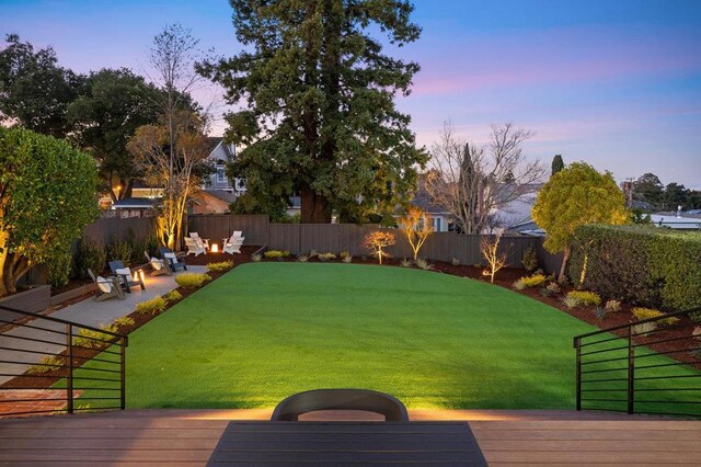 yard at dusk featuring a patio, a deck, and an outdoor fire pit