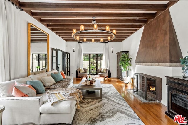 living room with beamed ceiling, a notable chandelier, and light wood-type flooring