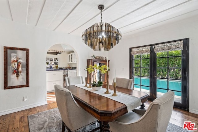 dining area featuring beamed ceiling, an inviting chandelier, light wood-type flooring, and french doors