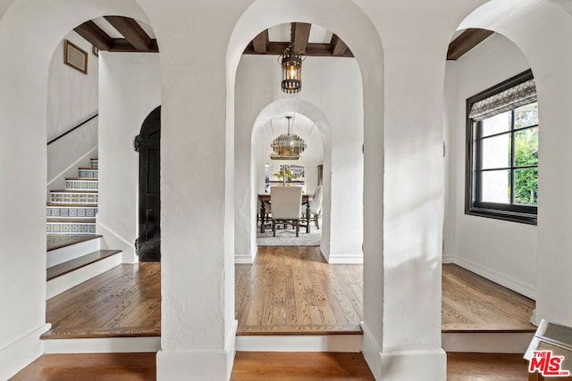 foyer with wood-type flooring and beam ceiling