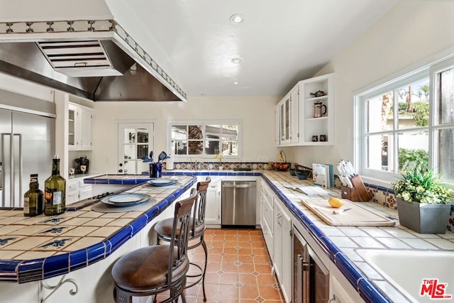 kitchen with stainless steel appliances, tile counters, and white cabinets