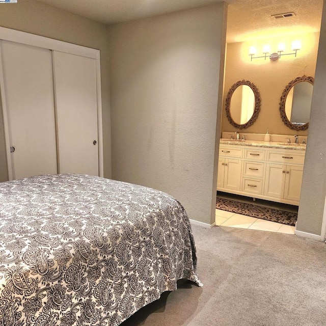 carpeted bedroom featuring ensuite bathroom, sink, and a closet