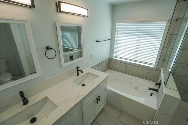 full bath with double vanity, a tub with jets, a sink, and toilet