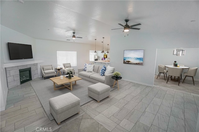 living area featuring a ceiling fan, baseboards, and a tiled fireplace