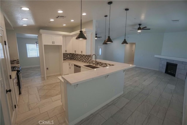 kitchen featuring a tile fireplace, a peninsula, a sink, visible vents, and appliances with stainless steel finishes