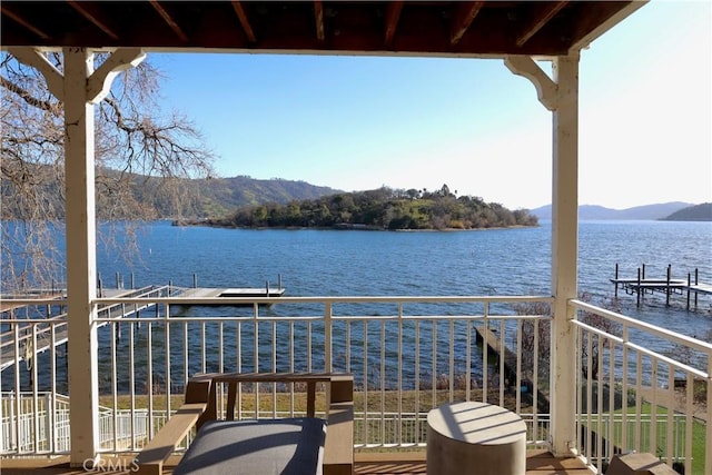 balcony featuring a water and mountain view and a dock