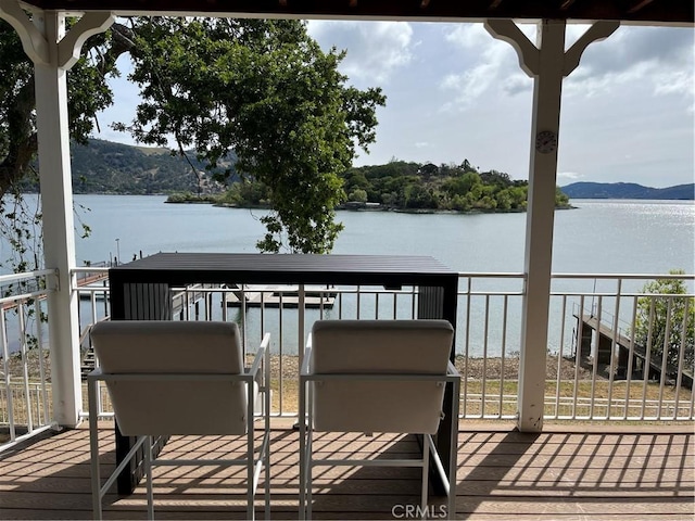 wooden deck with a water and mountain view