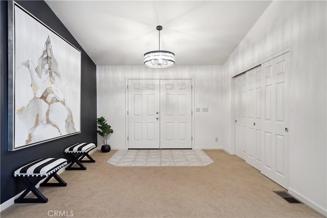 carpeted foyer with a chandelier