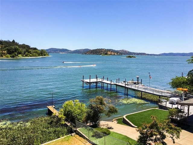 dock area with a water and mountain view and a yard