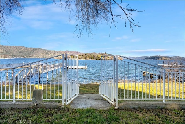 dock area featuring a water and mountain view and a lawn